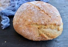 a loaf of bread sitting on top of a wooden table next to a blue cloth