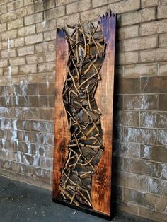 a piece of art made out of sticks and wood on the side of a brick wall