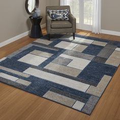 a living room area with a chair and rug on the hardwood floor, in front of a window