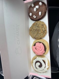 four cookies in a box with pink and white frosting