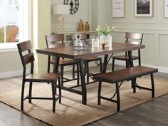 a dining room table with four chairs and a bench in front of it on a rug