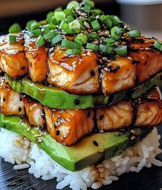 salmon and cucumber with sesame seeds on top of rice in a black plate