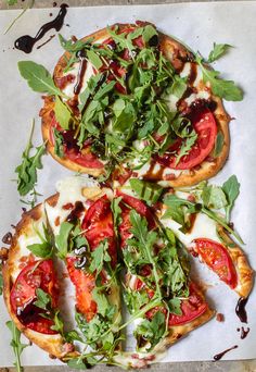 four slices of pizza with various toppings on them sitting on top of a piece of parchment paper