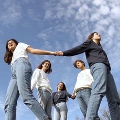 four girls are holding hands while standing in a circle with their arms extended and looking up at the sky