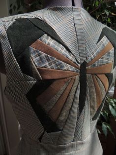 the back of a dress made out of different fabrics and fabric strips, with a bow at the neck