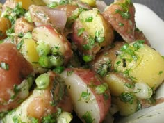 a white bowl filled with potatoes and green onions