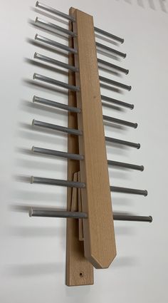 a wooden rack with metal rods hanging from it's sides on a white wall