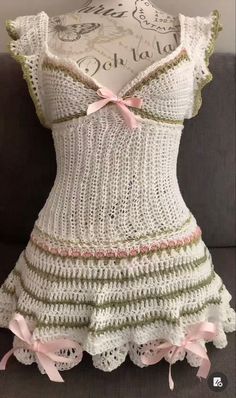 a dress made out of crochet with pink bows on the front and bottom