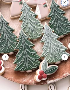 cookies decorated with christmas trees and snowflakes are on a platter next to cookie cutters