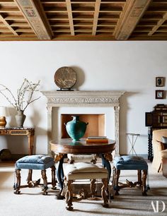 a dining room table with blue chairs and a vase on top of it in front of a fireplace