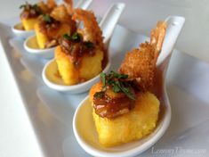 three small plates with food on them sitting on a white tablecloth covered trays