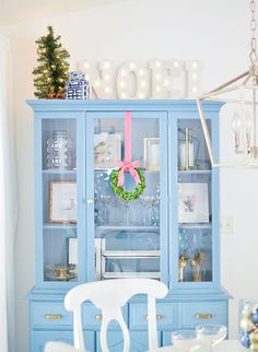 a blue china cabinet with a wreath on the top and lights hanging from it's sides