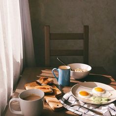 an image of breakfast setting on the dining room table with eggs and toast in mugs