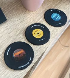 three black records sitting on top of a wooden table next to a pink cup and plant