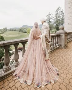 a bride and groom standing on a balcony looking out at the golf course from their wedding dress