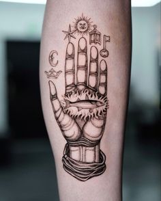 a tattoo on the leg of a person with a hand holding keys and symbols in it