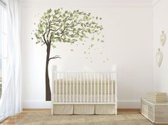 a baby's room with a white crib and tree decal on the wall