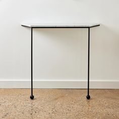 a white table sitting on top of a wooden floor next to a black metal frame