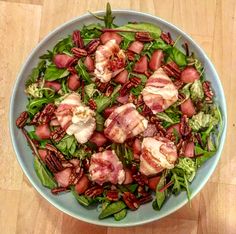 a salad with bacon, lettuce and pecans in a blue bowl on a wooden table