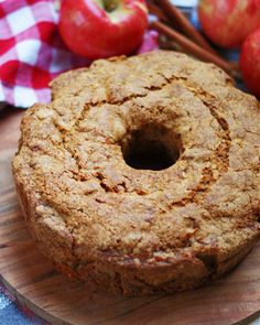 an apple cider cake sitting on top of a wooden cutting board next to apples