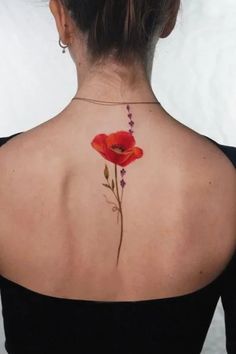 a woman with a flower tattoo on her back shoulder and behind her neck is a red poppy