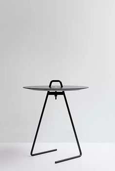 a round table with black metal legs and an oval glass top on the bottom, against a white background