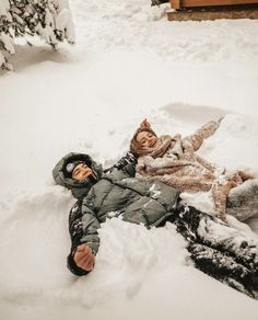 two people are laying in the snow together