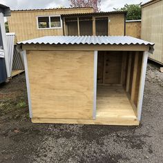 a wooden shed sitting in the middle of a yard with a metal roof and door