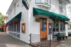 a white building with green awnings and flowers on the front door is shown