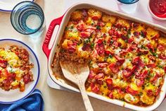 a casserole dish with meat and vegetables in it on a table next to water bottles