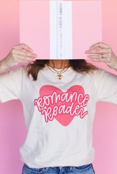 a woman holding up a book over her head with the words romance reader printed on it