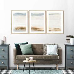 three paintings hang on the wall above a couch