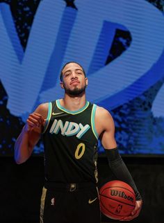 a man holding a basketball in his right hand and wearing a black jersey with the number 0 on it