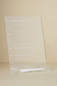 a clear acrylic sign sitting on top of a table next to a pen