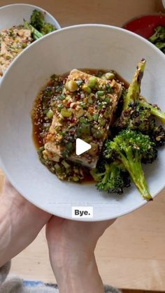 a person holding a plate with broccoli and meat on it in their hands