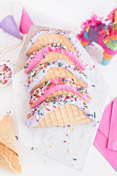 ice cream cones with sprinkles and pink frosting on a marble platter