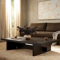 a living room with a couch, coffee table and rug in front of the window