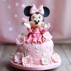 a minnie mouse figurine sitting on top of a pink cake