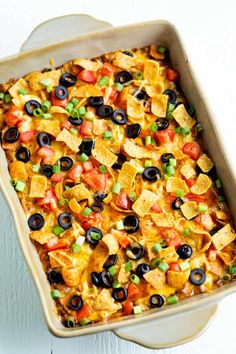 a casserole dish filled with nachos and black olives