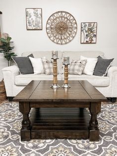 a living room with couches, coffee table and pictures on the wall above it