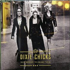 two women walking down the street in front of a store sign that says dixie chicks not ready to make nice