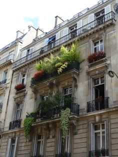 an apartment building with plants growing on the balconies