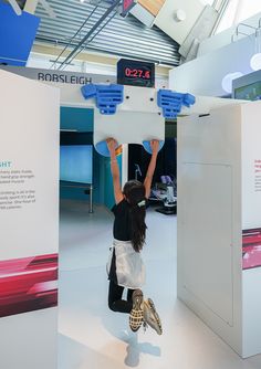 a woman reaching up into the air with her hands on top of a display board