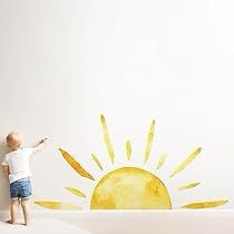 a little boy standing in front of a wall with the sun painted on it