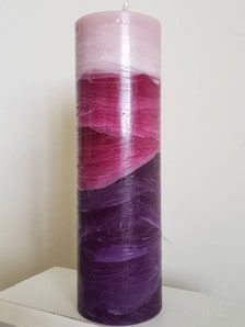 a purple and pink candle sitting on top of a white shelf