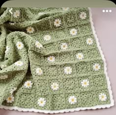 a crocheted blanket with daisies on it