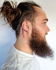 a man with long hair and a beard has a tattoo on his ear