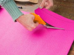 a person cutting fabric with scissors on a pink mat