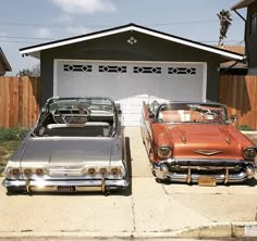 two old cars are parked in front of a house with a garage door on the other side