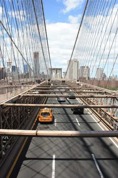 an orange taxi cab driving across the brooklyn bridge